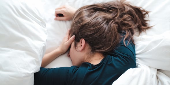 woman-laying-in-bed-holding-her-head_t20_8dn1z6